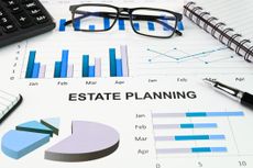 The words 'estate planning' on papers with bar graphs and pie charts 