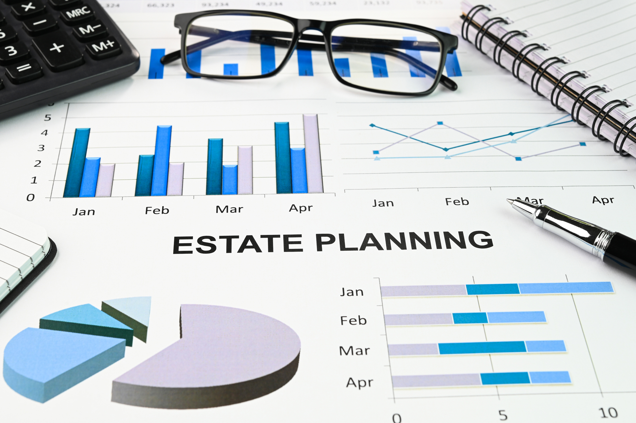 The words &#039;estate planning&#039; on papers with bar graphs and pie charts