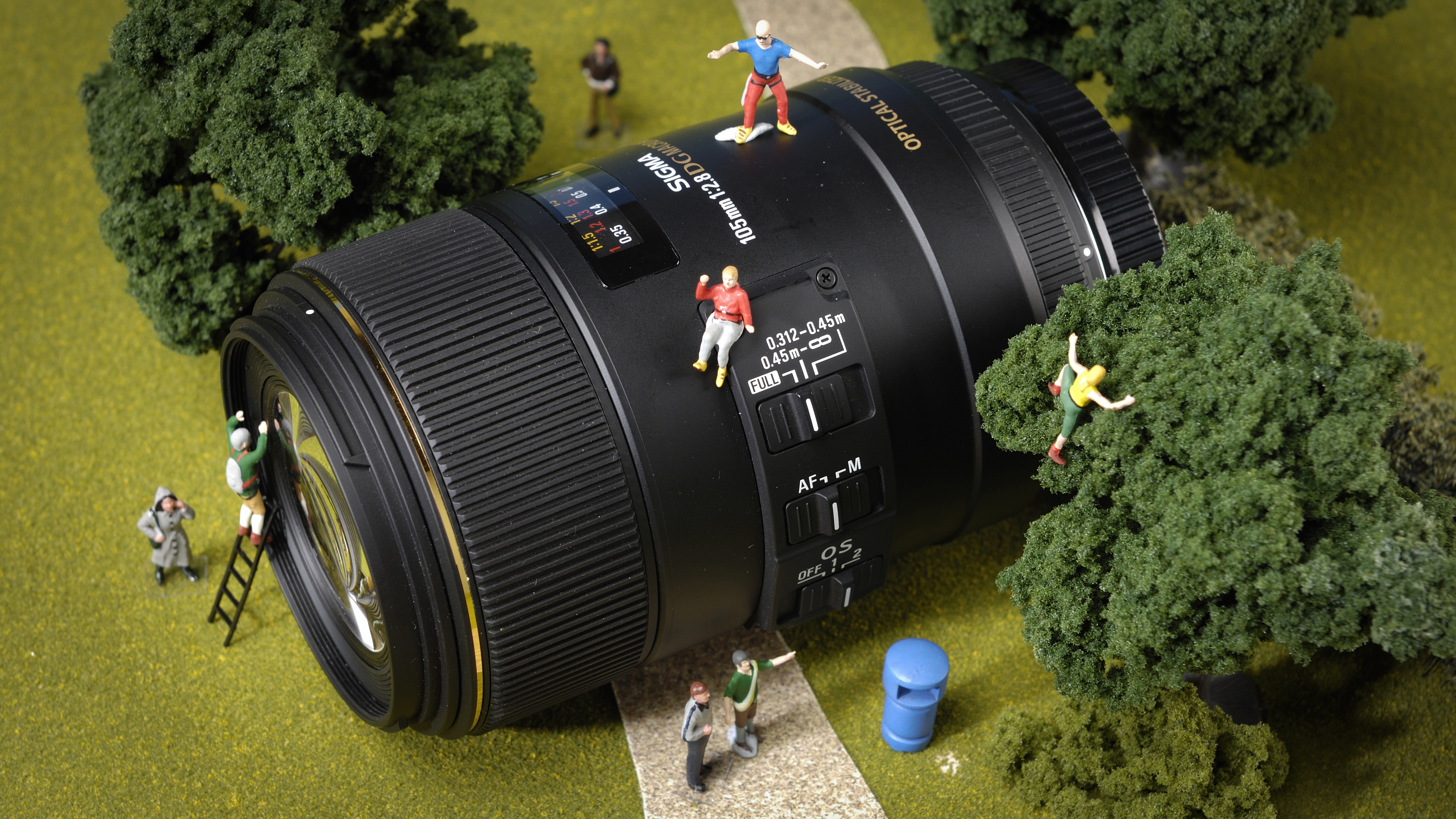 A Sigma macro lens decirated with miniature figures climbing over it