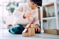 Child with black hair playing with wooden blocks