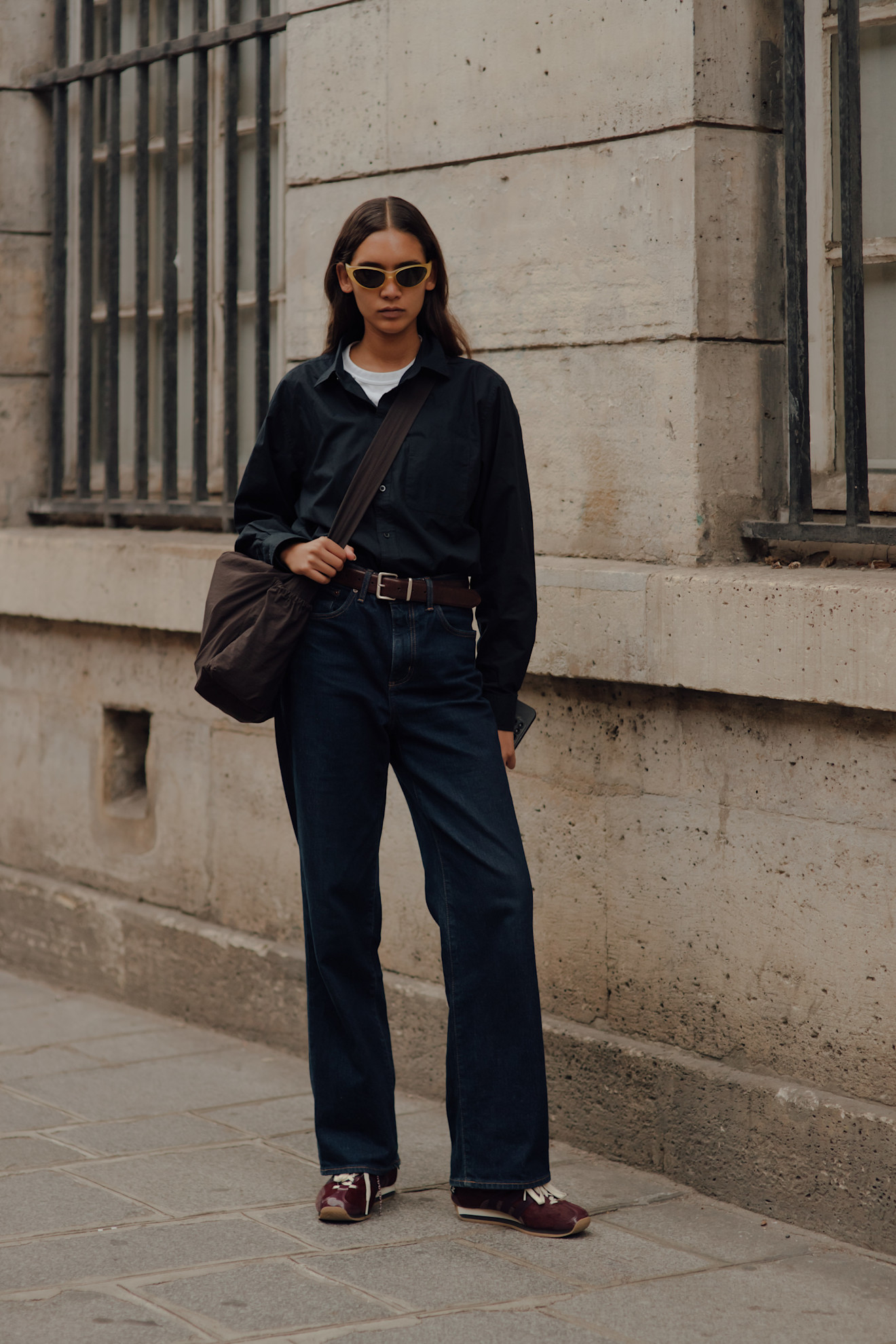 woman wearing black pants, black sneakers, and a black shirt over a white t shirt