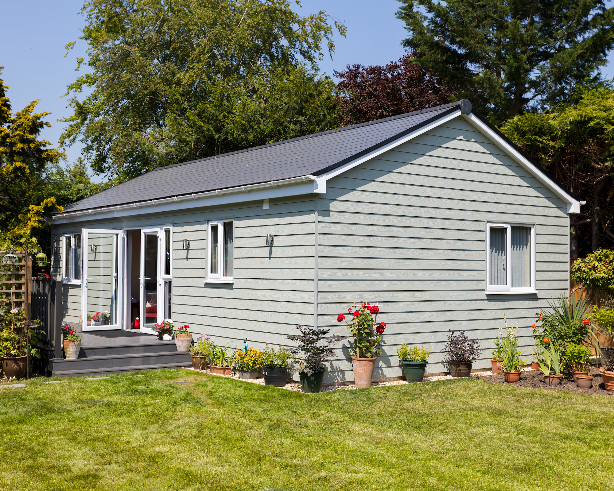 Annexe in garden with grey exterior and potted plants around it