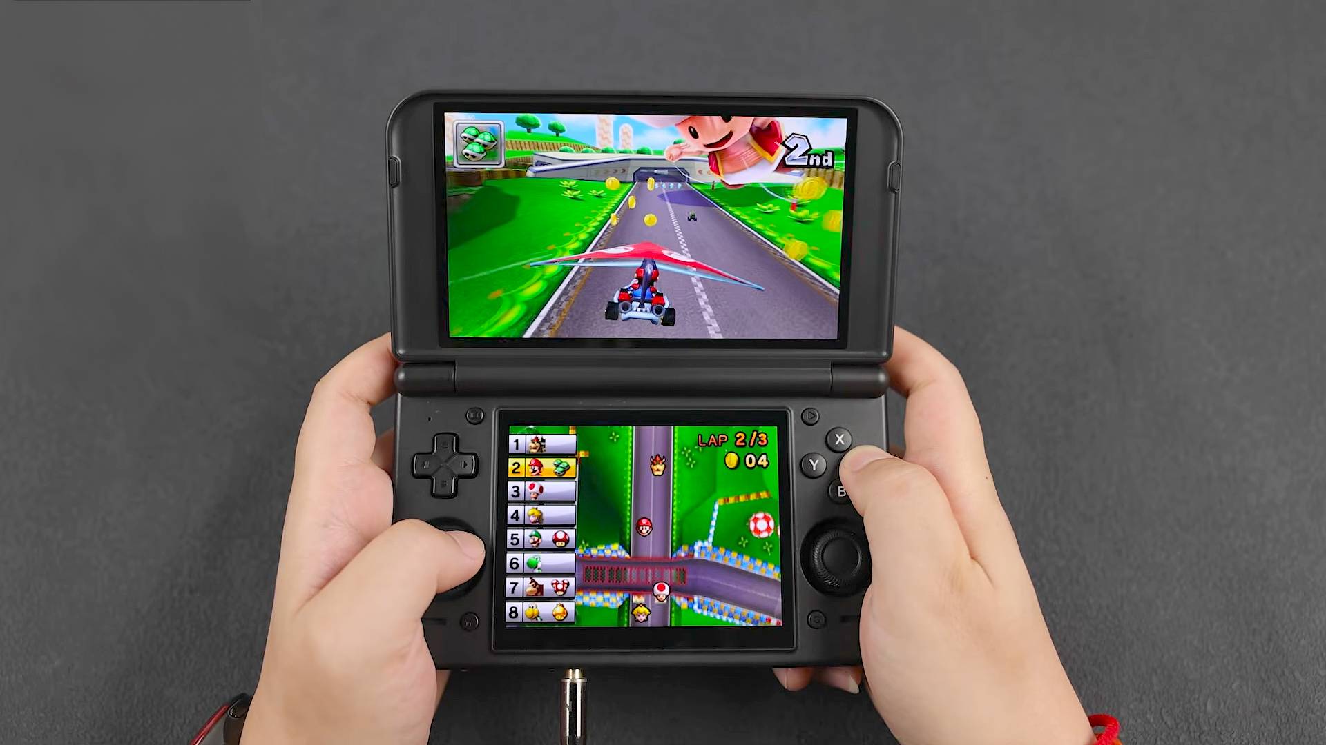 Hands using Retroid Pocket Duo Lite to play Mario Kart 7 with Mario using glider.