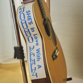 The sticker reading ’She's in love with a rodeo man’ that adorns the side of the guitar