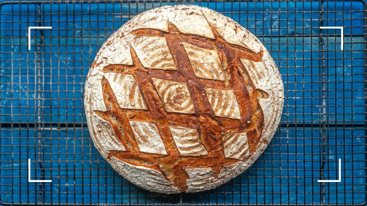 A loaf of sourdough bread sitting on black metal wire rack, to illustrate which foods reduce stress