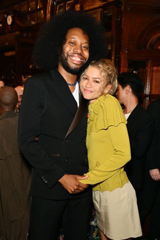 Zendaya poses with playwright jeremy o harris wearing a green sweater and summer's tall boot trend