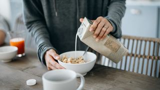 Person pouring oat milk into a bowl