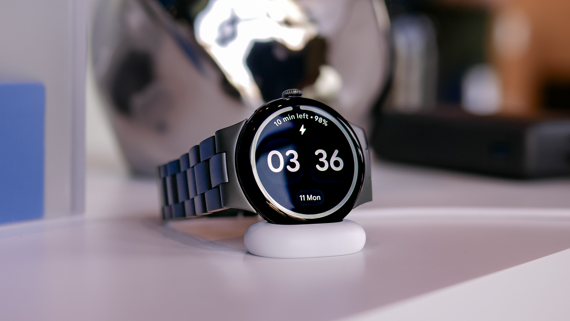Close-up shot of the Google Pixel Watch 4 in black shown charging on its side