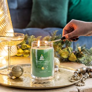 Yankee Candle being lit on a table surrounded by Xmas decorations