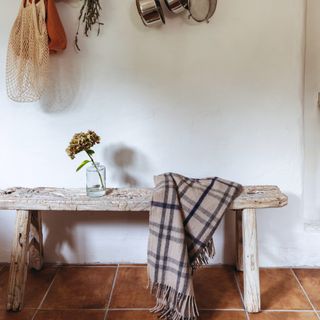 Tartan blanket draped over bench in rustic kitchen
