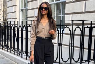 Woman wearing a collared sweater and high waisted black trousers.