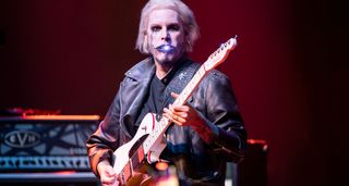 John 5 performs in a biker jacket with his white Ghost Telecaster – and a blue light in his mouth.