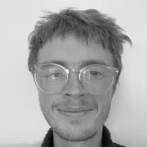black and white image of male with short hair wearing glasses