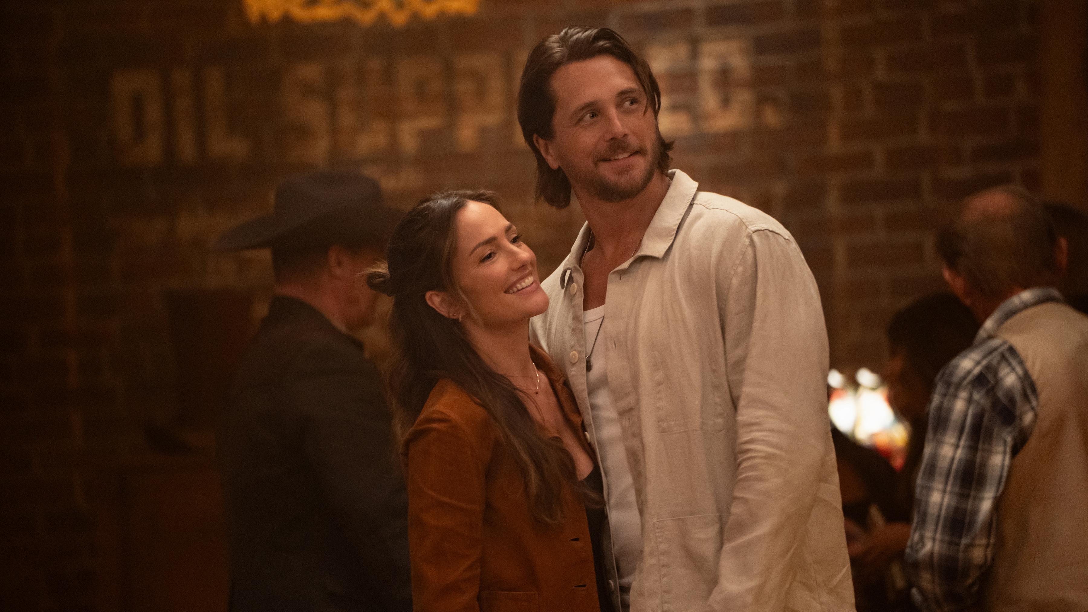Minka Kelly as Quinn and Ben Robson as Oliver smiling at something off camera while standing close together.