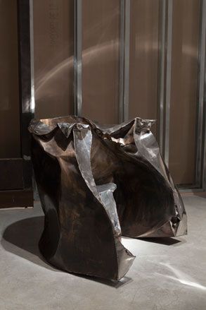 Curved sculpture consisting of metal and with a crumpled appearance