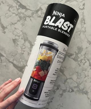 Ninja Blast portable blender cylindrical packaging on marble worktop held by Heather Bien
