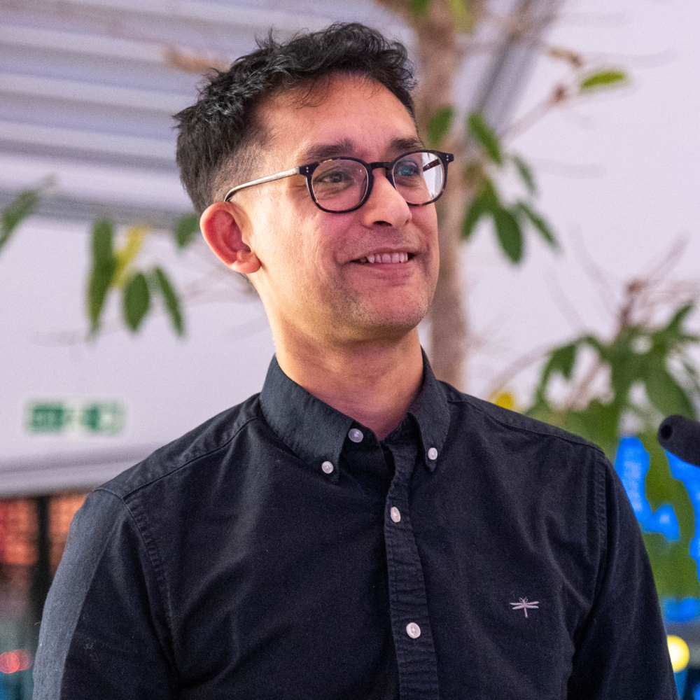 male with short dark hair wearing glasses and black shirt