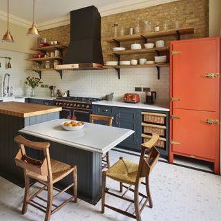 country kitchen with dark cabinets exposed brick wall and an orange vintage fridge