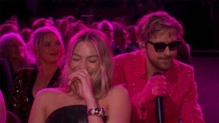 Margot Robbie laughing while Ryan Gosling performs "I'm Just Ken" at the 2024 Oscars.