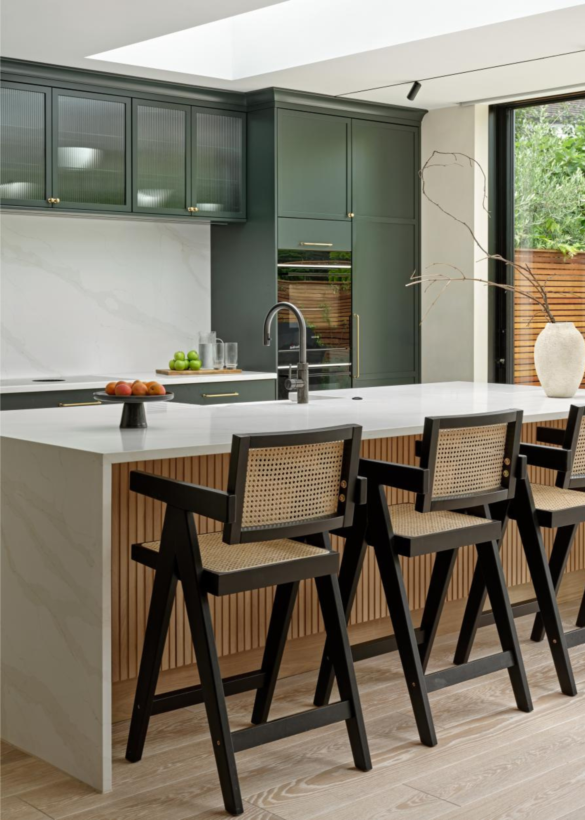 beautiful kitchen extension with green cabinetry and white marble surfaces