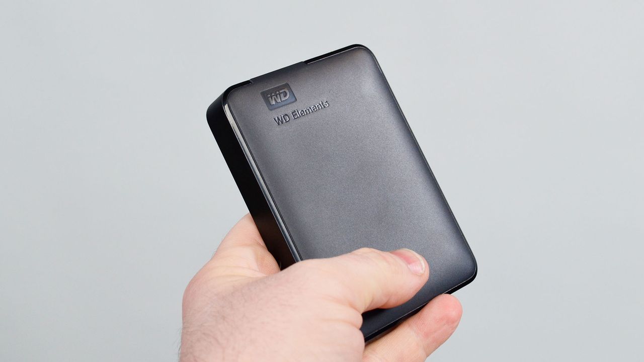 A msculine hand holding a WD Elements external hard drive