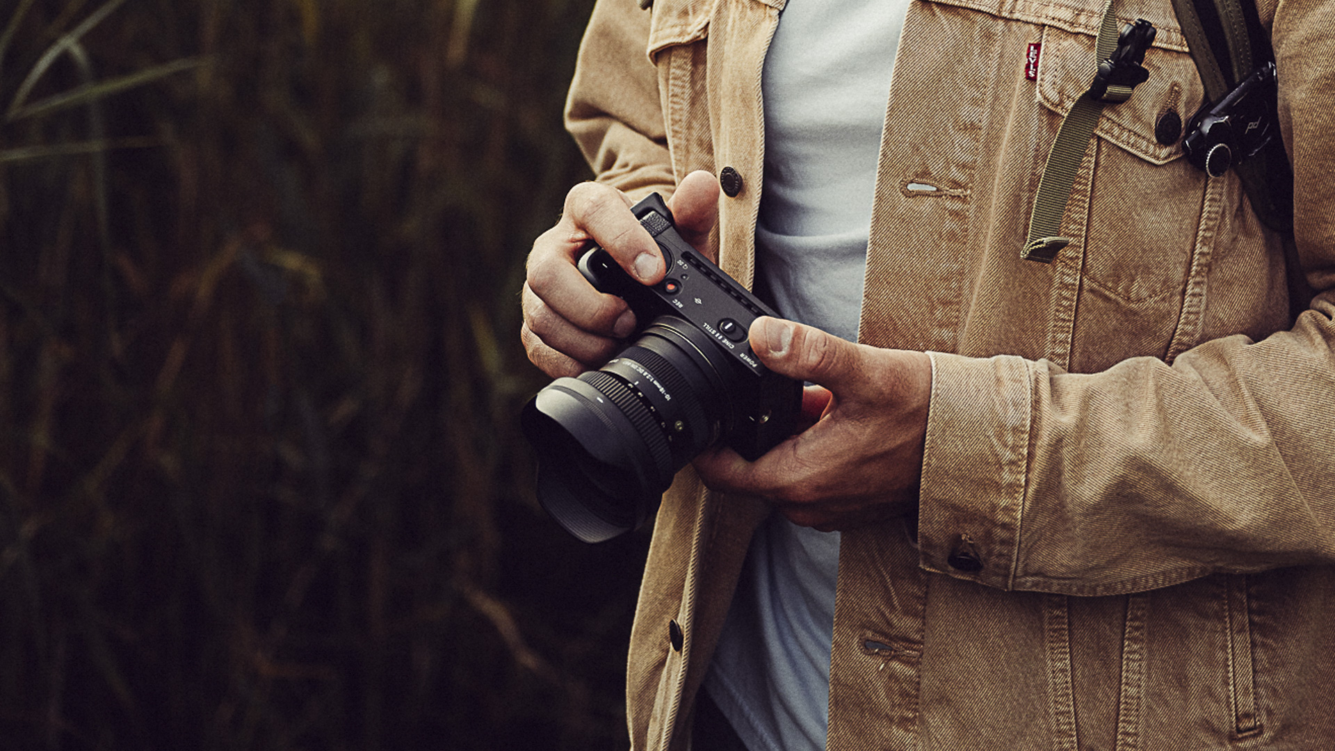 Sigma 10-18mm f/2.8 DC DN lens in the hand, outdoors, soft light