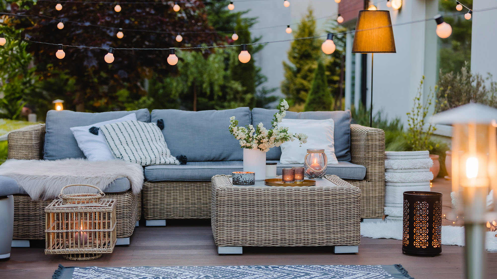Summer evening on the patio of beautiful suburban house with garden showing layered lighting