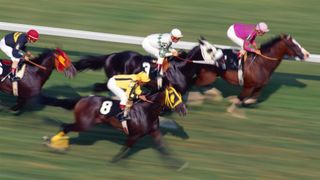 An aerial shot of multiple horses with jockeys racing on a track