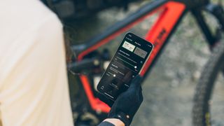 Hand holding iPhone with app for SRAM Eagle Powertrain displayed