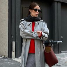 Influencer Anna Belrosendahl wears a red sweater, grey trench coat, and scarf. 