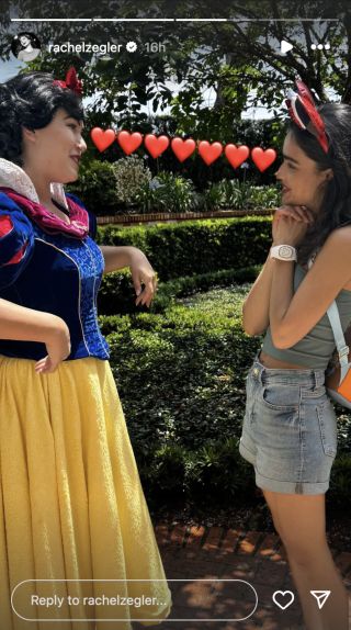 Disney World Snow White standing with Rachel Zegler talking. A line of emoji hearts between their faces.