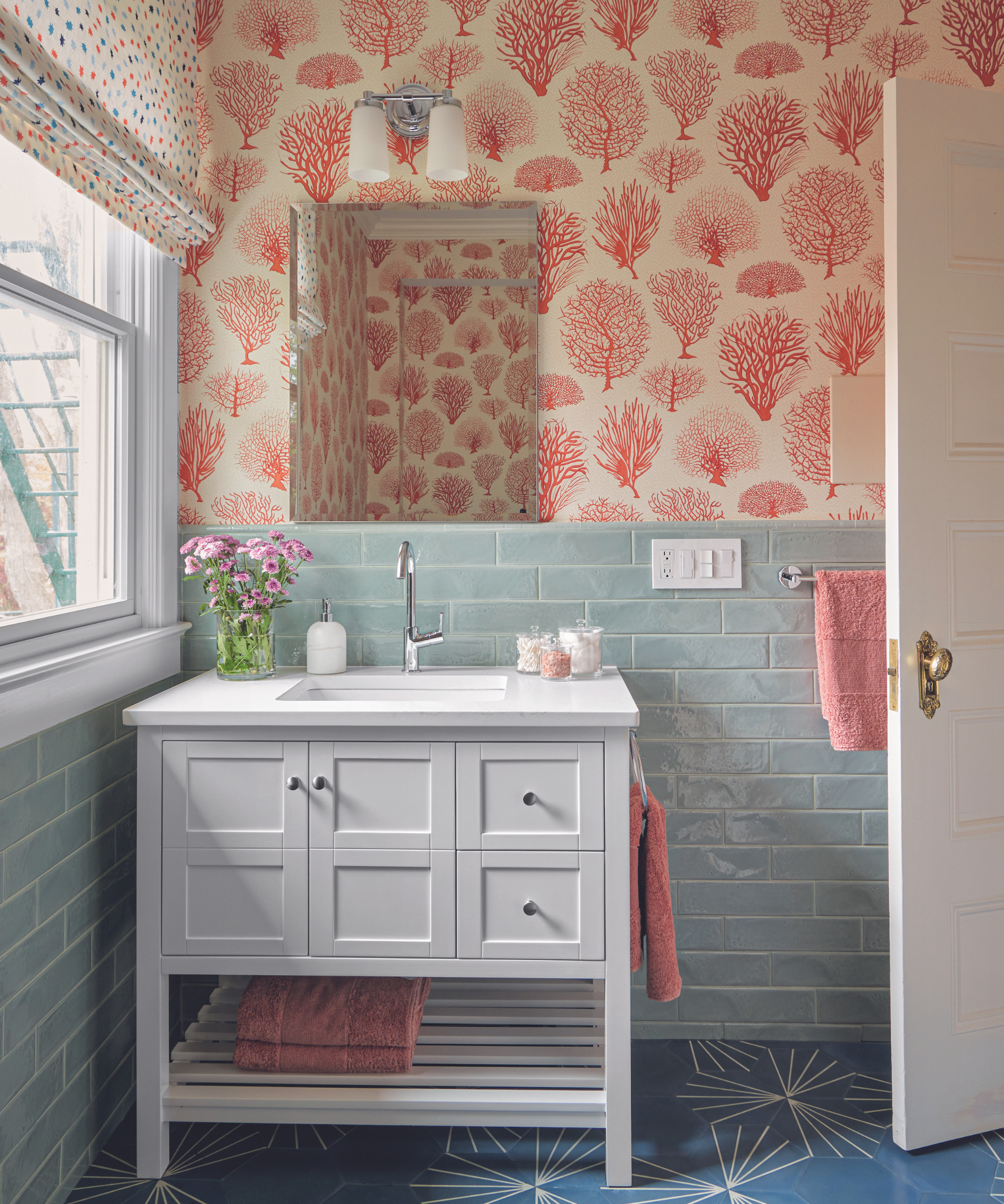 bathroom with seaweed print wallpaper in red with blue tiles and white sink unit and dark blue star pattern flooring