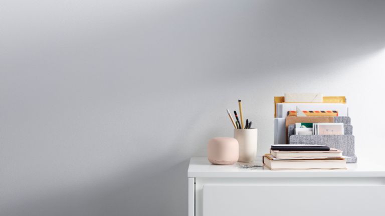 best mesh wifi system Google Nest Wifi in pink on white surface beside books and letters