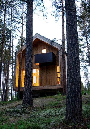 The Zerhouse Project by Huus Og Heim Architects, Norway. A double storey wooden cabin in a forest surrounded by trees.
