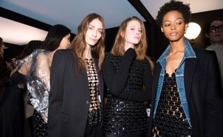 Models wear a range of black chainmail tops and dresses, layered with black blazers and denim shirts