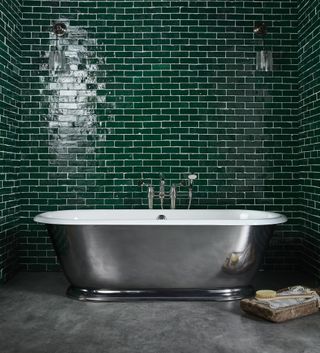freestanding silver finish bath in bathroom with emerald green tiles