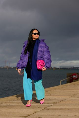 best down jackets, woman wearing purple puffer coat with blue pants and pink heels