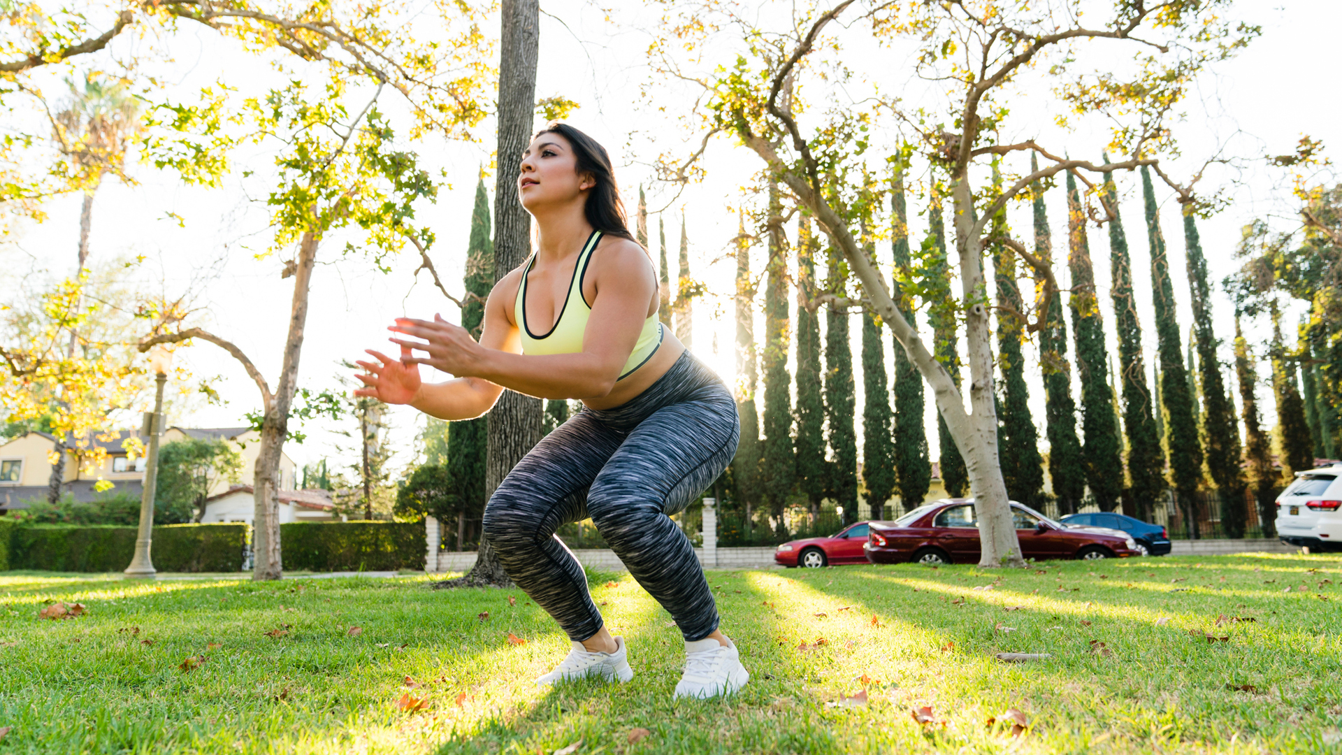 woman performing a jump squat in a park