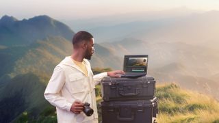 A man using the Asus ProArt PX13 with camera gear in a field outdoors