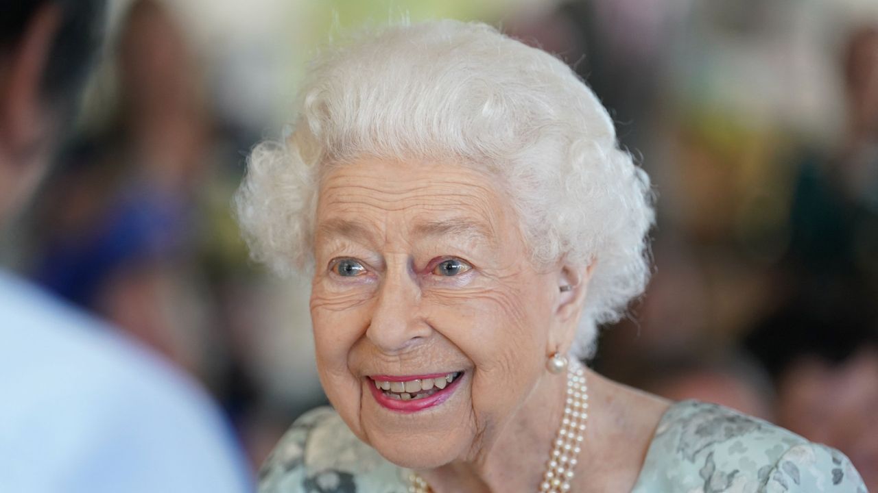 Glam Queen opts for pale blue frock and hot pink lipstick at hospice visit 