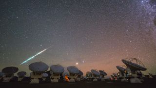 A time-lapse of the Atacama Large Millimeter/submillimeter Array (ALMA) used to detect the distant water, a cosmic fireball is seen streaming across the sky at the bottom left.