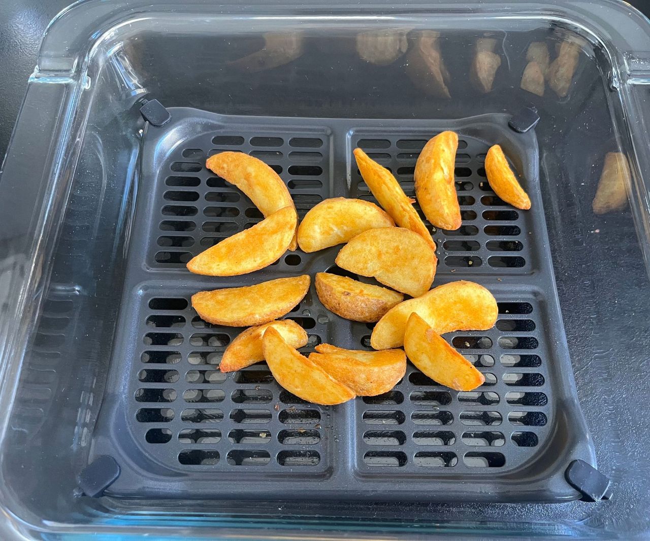 Chunky potato wedges on a black air fryer crisper tray