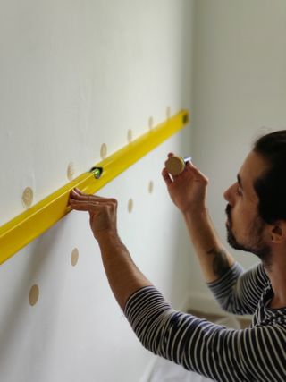 Creating a DIY Polka dot accent wall with sponge and gold paint