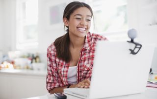 Woman smiling as she uses a laptop