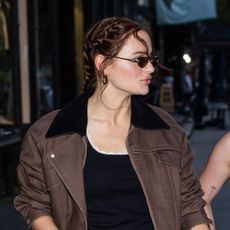Joey King wearing a brown jacket, jeans, and black sandals