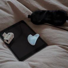 A gua sha, a breakfast tray, and a woman in her pajamas in bed