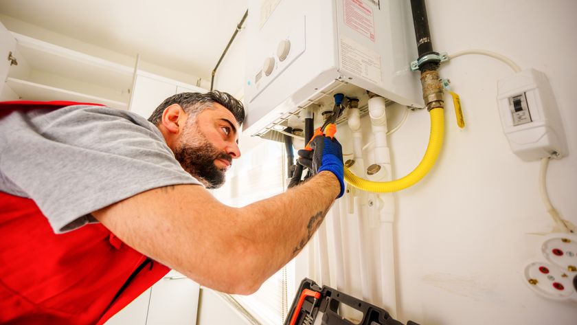 workman working on boiler mounted on wall