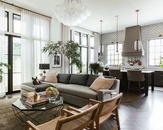 open-plan living room and kitchen with white walls, gray sofa, dark cabinets and modern decor