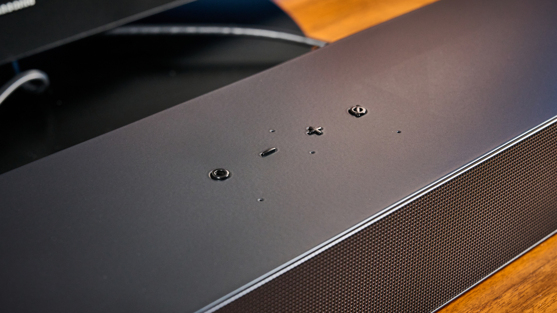 the samsung hw-s60D soundbar photographed on a wooden coffee table with a panasonic tv and a samsung soundbar against a blue background