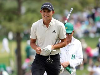 Collin Morikawa with his caddie, holding a putter at Augusta National